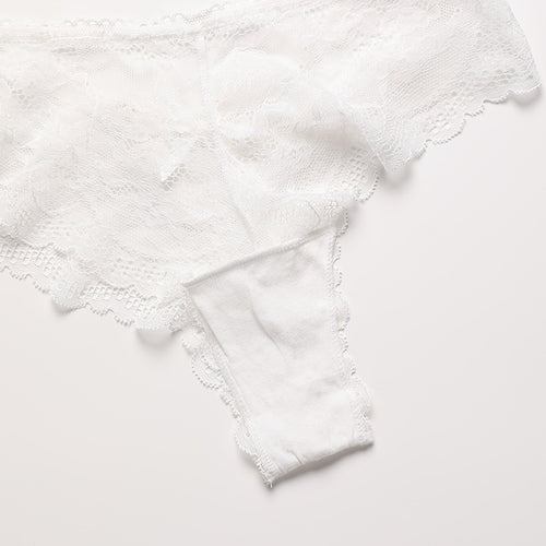 Flat lay presentation of the KissKismet romantic sheer white lace thong, detailing the beautiful floral pattern and scalloped trim.